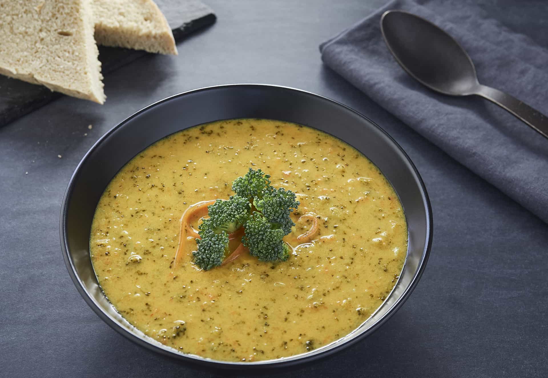 Broccoli soup with bread and cheese on black.